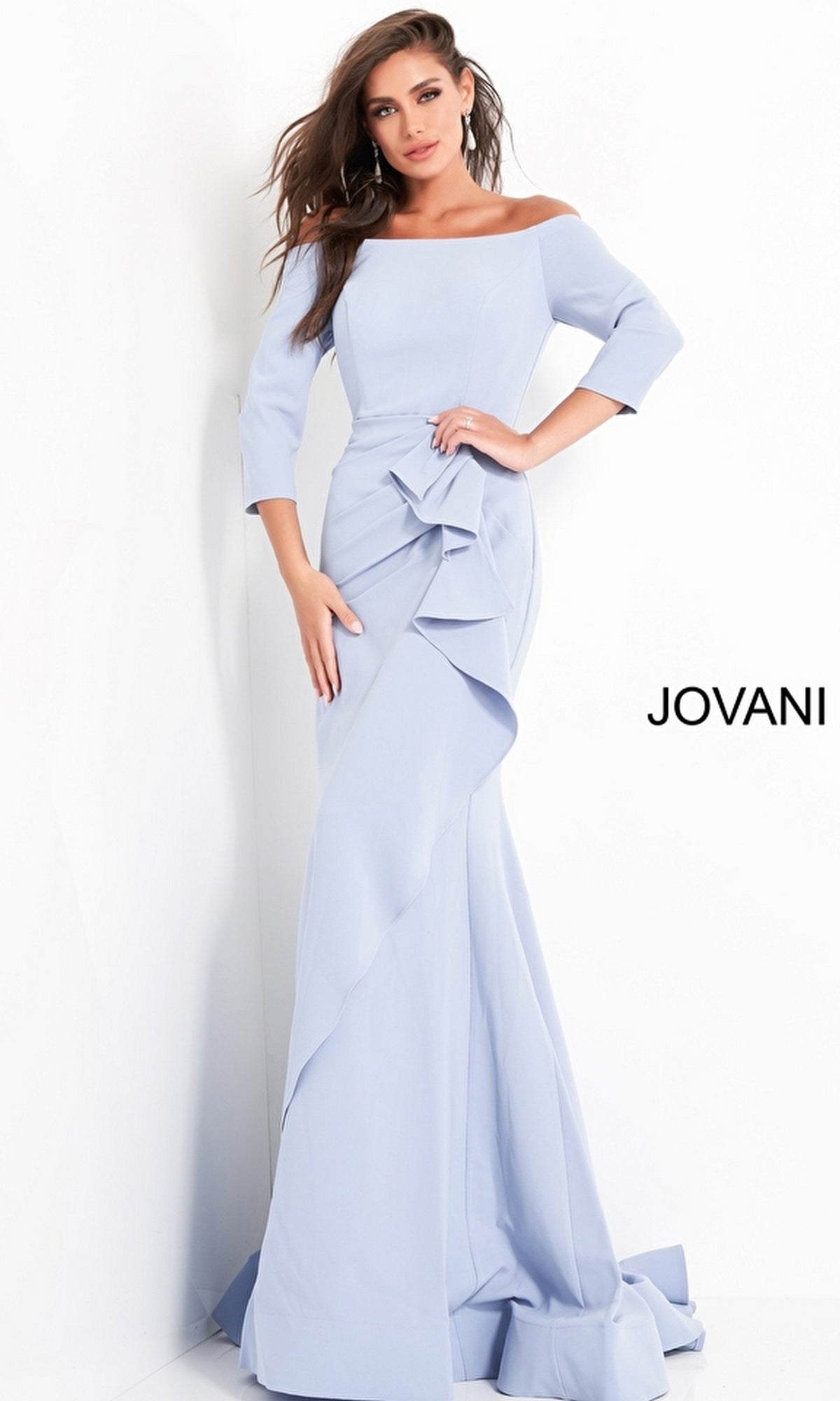 A woman wears the Jovani Mother-of-the-Bride Long Formal Dress 00446 in light blue, featuring an off-the-shoulder design with ruffle details, standing against a white background.
